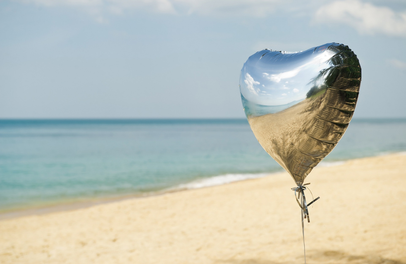 A single heart shaped balloon on a beach