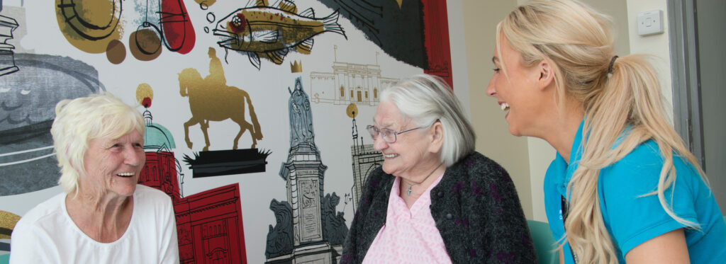 Two elderly ladies laugh with a younger woman