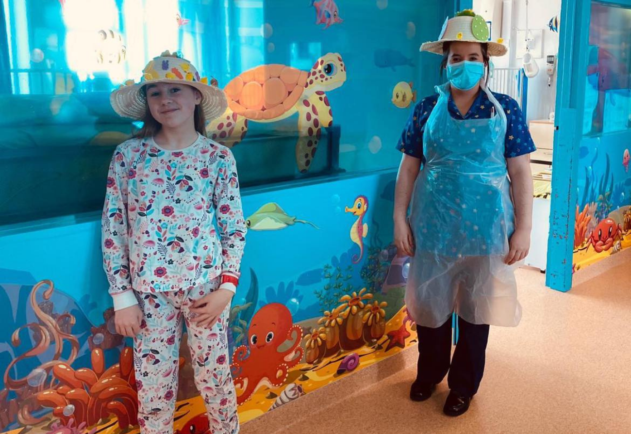 A child and a nurse wear Easter hats