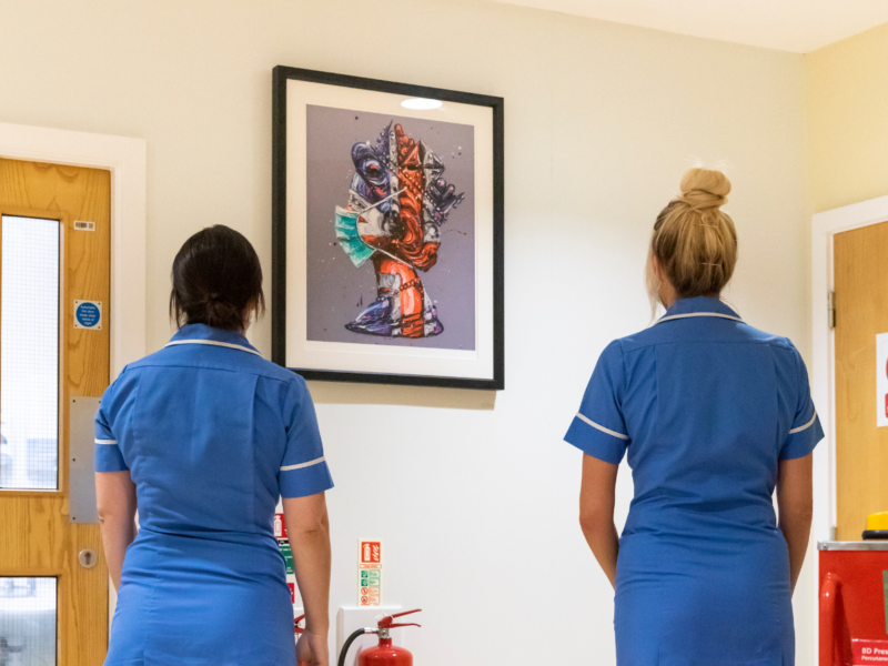 Two nurses look at the Corona Queen artwork
